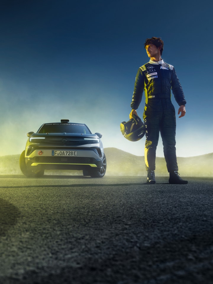 Ein Frontshot des Mokka GSE Rally mit einem Rallyefahrer daneben, der einen Helm hält