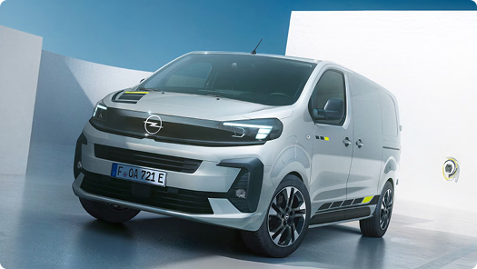 Ein silberner Opel Vivaro, schräg geparkt in einer modernen Studiokulisse vor einem blau-weißen Hintergrund.